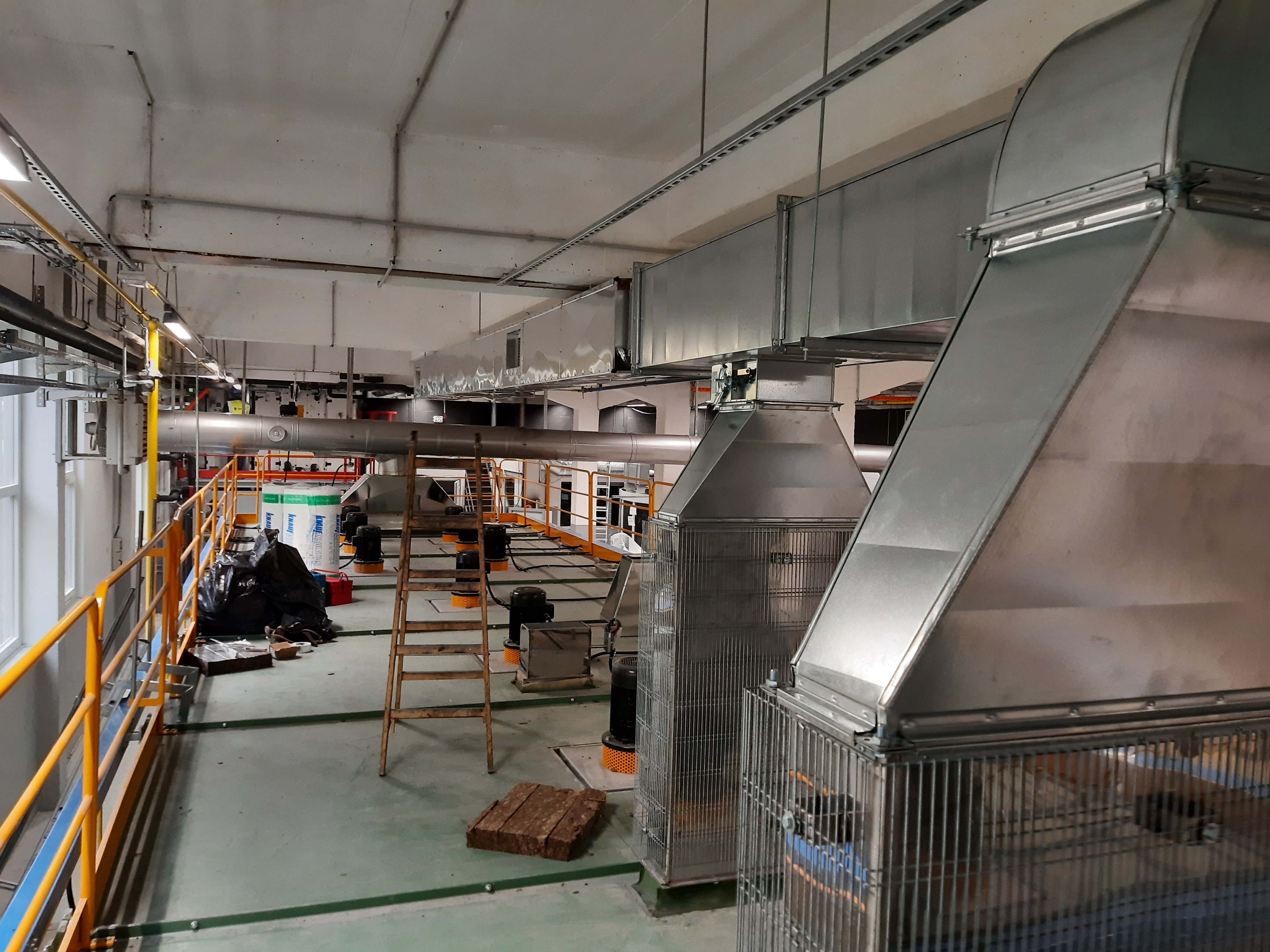 Razvejan sistem kovinskih prezračevalnih kanalov v industrijskem prostoru